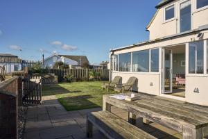 a patio with a wooden bench and a house at Harbour Lights in Southwold