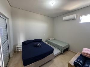 a small room with a bed and a small bed and a window at Suites dos Laranjais in Olímpia