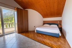 een slaapkamer met een bed en een groot raam bij Beach Apartments Villa Holiday in Živogošće