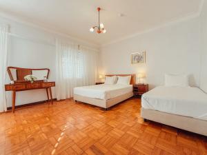 a bedroom with two beds and a wooden floor at Casa do Lugar de Paços in Caldelas
