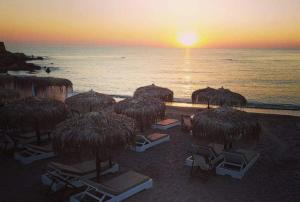 a group of straw umbrellas and chairs on the beach at EmvaSea Seaside apartment in Monemvasia