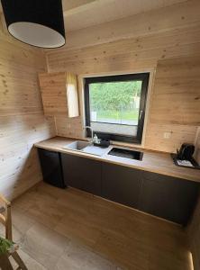 eine kleine Küche mit Spüle und Fenster in der Unterkunft Szare Domki in Mrzeżyno