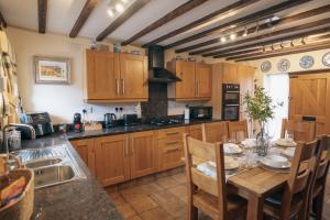 a kitchen with wooden cabinets and a table with chairs at The Old Mill at Barnacre - Cosy cottage with private hot tub & pool access in Wirral