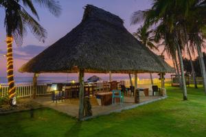 un ristorante con tetto di paglia, tavoli e sedie di Mangomar Beach House a Teotepeque