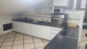una cucina con mobili bianchi e un piano di lavoro nero di Lena apartment a Vojnica Altre 8 foto