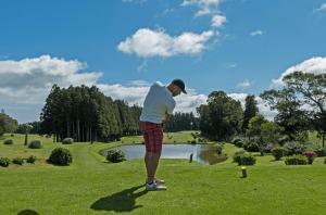 a man is playing golf on a golf course at Apartamentos em Casa da Avó Inês in Porto Formoso