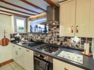 a kitchen with white cabinets and a stove top oven at Fellside Cottage in Bowness-on-Windermere