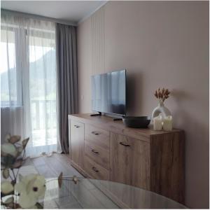a living room with a television on a wooden dresser at Апартамент "Rodopi" с Гледка към Езеро Безплатен Подземен Гараж in Smolyan +64 photos