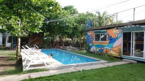 a swimming pool with white chairs next to a building at Green Belly Surf Hostel in El Paredón Buena Vista +27 photos