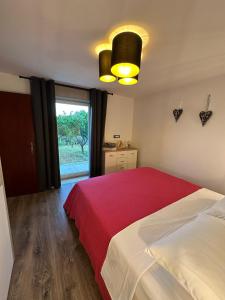 a bedroom with a bed with a red blanket and a window at Apartments Marija in Rabac