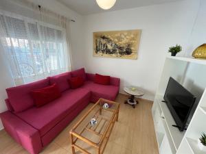 a living room with a purple couch and a tv at Villa Alcázar in San Pedro del Pinatar