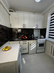 una cocina con armarios blancos y una bandeja de fruta en la barra en Апартаменты на Калдаякова, en Shymkent