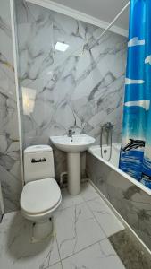 Un baño blanco con inodoro y lavabo. en Апартаменты на Калдаякова, en Shymkent