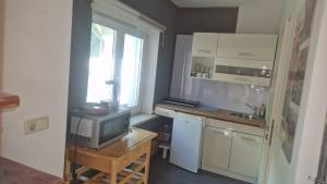 a small kitchen with a desk with a tv and a window at WOHLFÜHLOASE - Zimmer, Appartment - im Herzen STARNBERGS in Starnberg