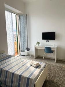 a bedroom with a bed and a desk and a tv at La Finestra sul Blu - Sea View in Savona