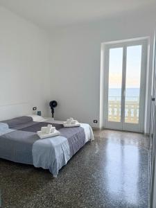 a white bedroom with a bed and a large window at La Finestra sul Blu - Sea View in Savona