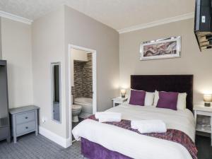 a bedroom with a large bed with purple pillows at Tennyson House in Scarborough
