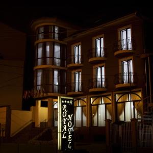 Un edificio con un cartel delante por la noche. en RHC Royal Hotel, en Oradea