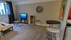 a living room with a tv and a table and chairs at Studio spacieux - Labronie in Sarlat-la-Canéda