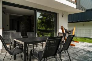 a black dining table and chairs on a patio at Guciowy Zakątek & SPA sauna, jacuzzi, tężnia in Zwierzyniec