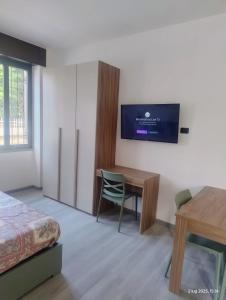 a bedroom with a desk and a tv on a wall at Malpensa Sleep & Go in Somma Lombardo