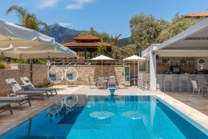 a pool with chairs and umbrellas next to a house at Supreme Luxury Suites in Skala Potamias