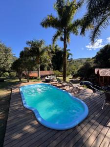 a swimming pool on a wooden deck with palm trees at Pousada Paraíso de Maua in Resende