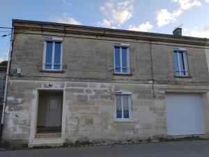 an old stone building with two white garage doors at De marées en marais in Bourg-sur-Gironde