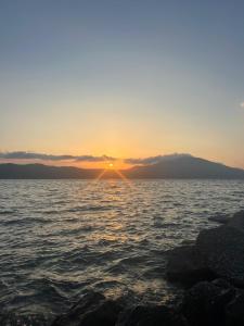 a sunset over a body of water with rocks at Dario's Apartaments 2 in Orikum +8 photos