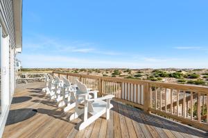 a row of white chairs sitting on a deck at Sandpiper in Salvo