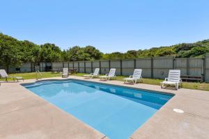 a swimming pool with lounge chairs and a fence at Savannah Dawn in Southern Shores