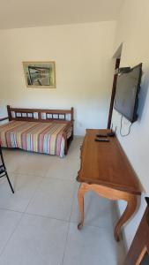 a bedroom with a bed and a table with a television at Turtle house 1 in Búzios