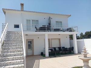 オ・グローベにあるApartamentos Albizia, Ideales para familias con niñosのバルコニーと黒い椅子のある白い家