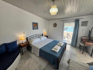 a bedroom with a bed and a couch and a window at Riva Blue Silence -Seafront Retreat in Poseidónion
