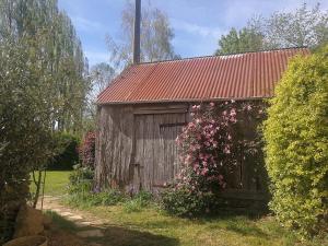 an old barn with a red roof and flowers at Maison Bretagne in Bourseul