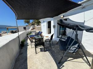 a patio with a table and chairs and an umbrella at Riva Blue Silence -Seafront Retreat in Poseidónion