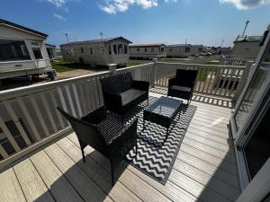 eine Terrasse mit drei Stühlen und einem Tisch darauf in der Unterkunft Meadow Lakes 76 - sleeps 6 with a bath - Golden Palm Resort - Meadow Lakes Caravan & Lodge Hire in Chapel Saint Leonards