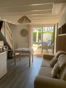 un salon avec un canapé et une table dans l'établissement Cottage cosy avec jardin, piscine et parking, à Cabourg
