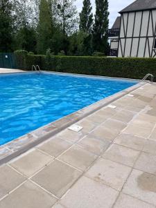 une piscine avec de l'eau bleue dans une cour dans l'établissement Cottage cosy avec jardin, piscine et parking, à Cabourg