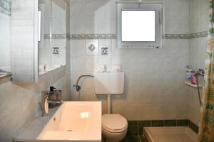 a bathroom with a sink and a toilet and a window at 50 Steps From the Sea in Lefkimmi +21 photos