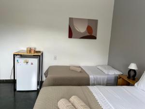 una habitación con dos camas y una nevera en Flat com ar, varanda e linda vista para o Ibituruna - Pico do Ibituruna - 201, en Governador Valadares