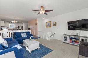 a living room with a blue couch and a tv at Sea Escape in Kill Devil Hills