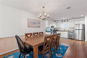 a dining room and kitchen with a wooden table and chairs at Sea Escape in Kill Devil Hills