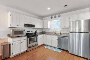 a kitchen with white cabinets and a stainless steel refrigerator at Sea Escape in Kill Devil Hills +19 photos