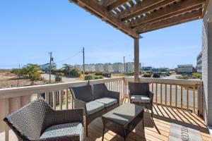 a deck with chairs and tables and a view of a street at Sea Escape in Kill Devil Hills