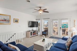 a living room with a blue couch and a tv at Sea Escape in Kill Devil Hills