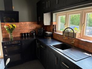 a kitchen with black cabinets and a sink at Cuilcagh Luxury Studio in Enniskillen +15 photos