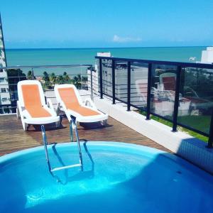 a swimming pool on a balcony with chairs and the ocean at Apartamento na Praia de João Pessoa in João Pessoa