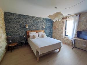 a bedroom with a bed and a tv in it at Charmante maison provençale proche d'Uzès in Garrigues-et-Sainte-Eulalie +14 photos