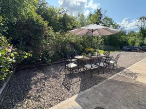 a table and chairs with an umbrella in a garden at Cuilcagh Luxury Studio in Enniskillen